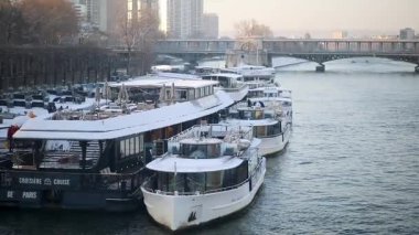 Paris, Fransa - 6 Ocak 2026: Karla kaplı çok sayıda nehir teknesinin Paris 'e yanaştığı kış manzarası.