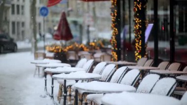 Paris 'te geleneksel açık büfe sandalyeleri ve yuvarlak masalar taze kar tabakasıyla kaplı.