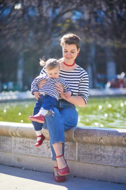 Güzel genç anne ve tapılası küçük kızı Paris, Fransa 'da parkta birlikte yürüyorlar.