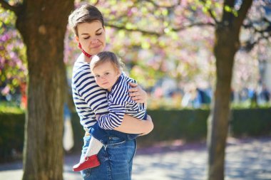Güzel genç anne ve tapılası küçük kızı Paris, Fransa 'da parkta birlikte yürüyorlar.