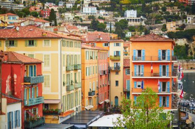 Akdeniz kıyısındaki bir kasabada mavi panjurları ve ulusal bayrakları olan renkli binaların canlı görüntüsü.