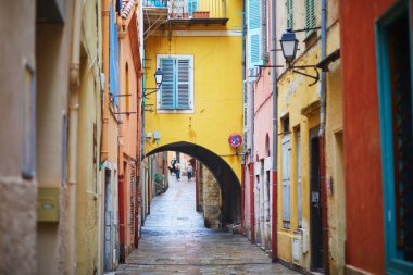 Akdeniz kıyısındaki bir kasabada mavi panjurları ve ulusal bayrakları olan renkli binaların canlı görüntüsü.