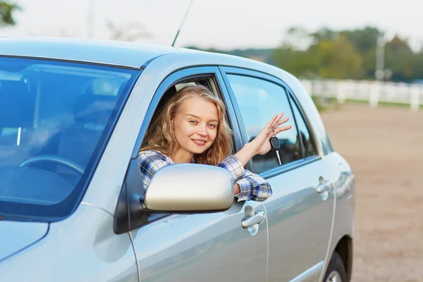 Женщина смотрит в окно машины и держит ключ — стоковое фото