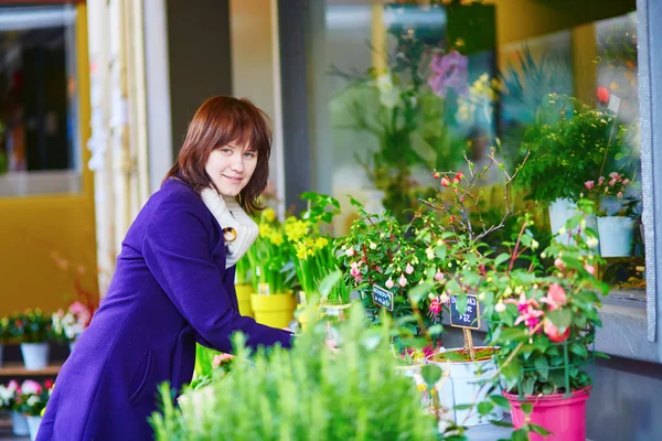 Beautiful young woman selecting flowers at market — Stock Photo, Image