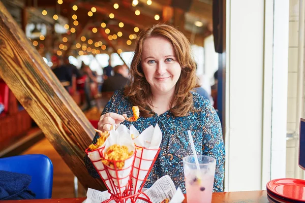 Chica alegre comiendo camarones fritos en el restaurante de mariscos —  Fotos de Stock