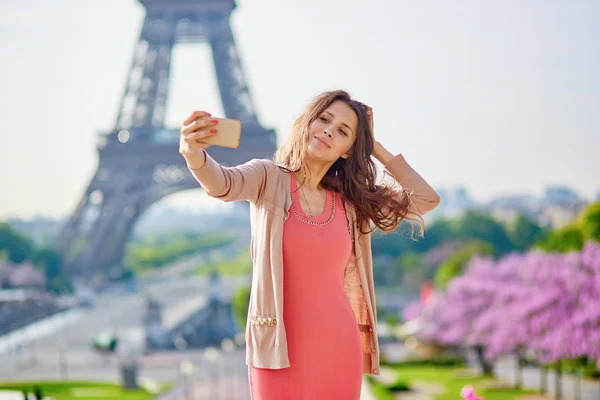 Mooie jonge vrouw in de buurt van de Eiffeltoren in Parijs met mobiele telefoon — Stockfoto