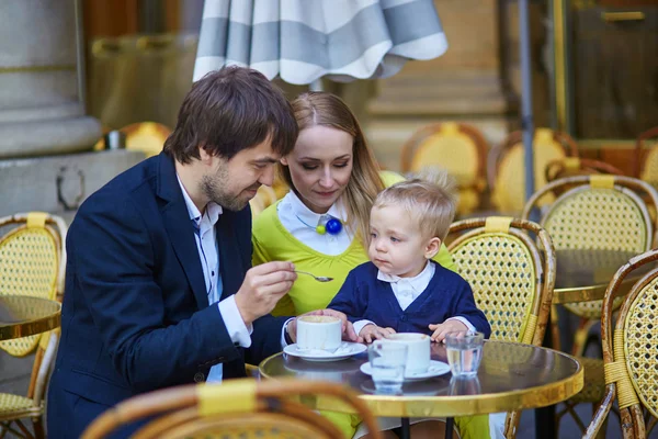 Familia feliz de tres en un café parisino al aire libre —  Fotos de Stock