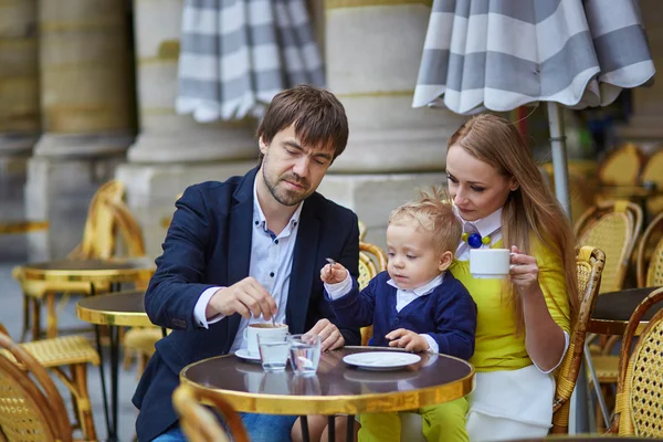 Счастливая семья из трех человек в открытом парижском кафе — стоковое фото