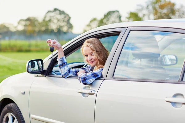 Unga förare ute ur bilen fönstret håller en nyckel — Stockfoto