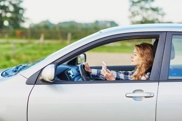 Žena pomocí její smartphone za jízdy auto — Stock fotografie