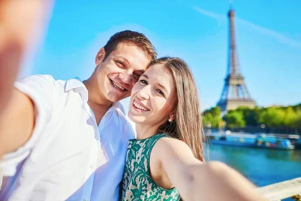 Jovem casal romântico tomando engraçadoselfie com telefone celular perto da torre Eiffel em Paris, França — Fotografia de Stock