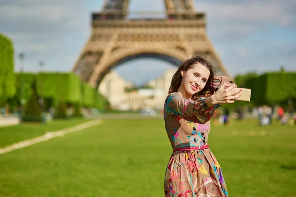 Красивая женщина возле Эйфелевой башни в Париже делает селфи с помощью мобильного телефона — стоковое фото