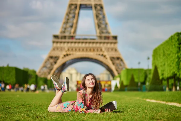 Mooie jonge vrouw in Parijs liggen op het gras in de buurt van de Eiffeltoren — Stockfoto