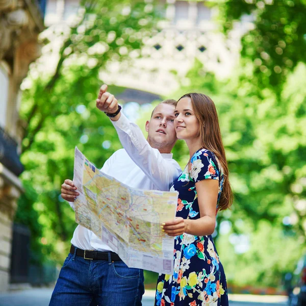Junges romantisches Paar mit Karte in der Nähe des Eiffelturms in Paris, Frankreich — Stockfoto