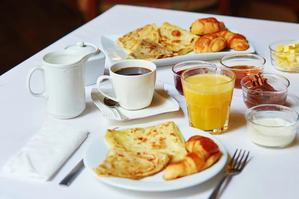 Сніданок з апельсиновим соком, випічкою, млинцями та кавою — стокове фото