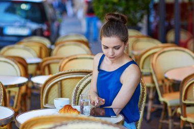 Beautiful young Parisian woman in cafe clipart