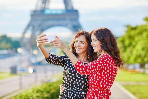 Hermosas hermanas gemelas tomando selfie frente a la Torre Eiffel — Foto de Stock