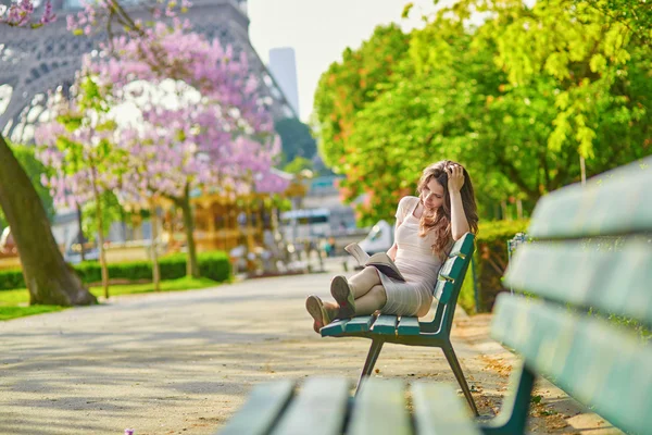 Mulher bonita em Paris lendo no banco ao ar livre — Fotografia de Stock