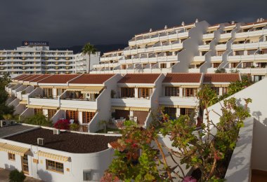 Koyu bulutlu arka planda beyaz otel binası.