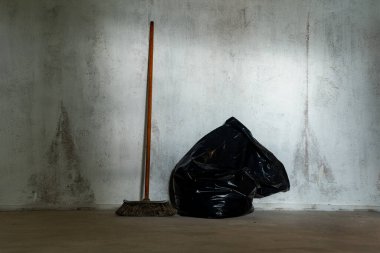 Doğal eski süpürge ve duvardaki büyük siyah plastik torba tamir zamanı..