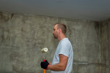 Boş bir dairede boya silindirli bir tamirci..