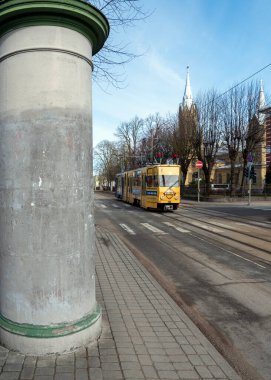 Liepaja, Baltık Denizi 'nde yer alan bir şehirdir. 18 Mart 2021 'de tramvay ve boş poster direğiyle sokağa bakın, Liepaja, Letonya.