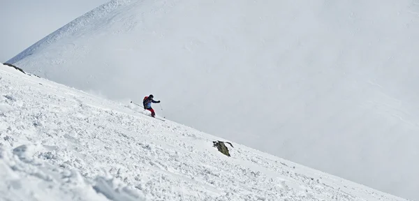 Sciatore uomo scivola giù dal fianco della montagna — Foto Stock