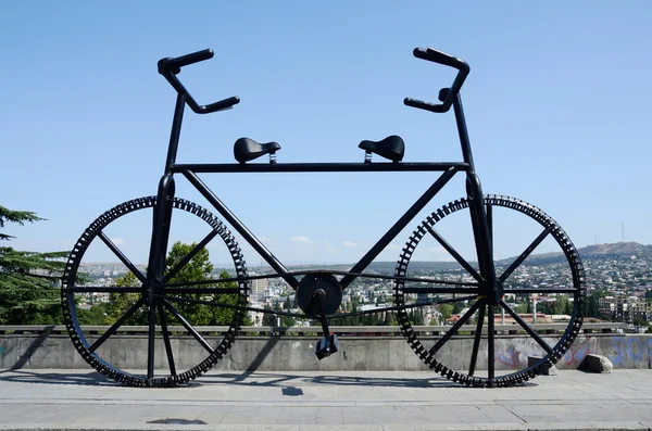 Gigantesca estatua de bicicleta con dos barras de manija y sillas de montar en la plaza de la Revolución de las Rosas en Tiflis, Georgia —  Fotos de Stock