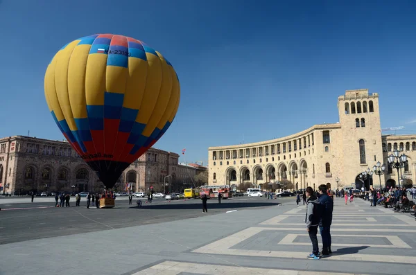 Yerevan, Armenië - maart 8,2015: Mensen lancering van kleurrijke hete luchtballon in de buurt van het regeringsgebouw op het plein van de Republiek (ontworpen door architect Alexander Tamanian), op 8 maart 2015 in Yerevan — Stockfoto