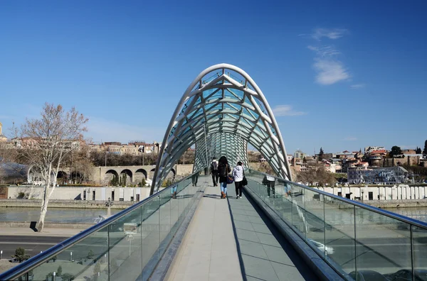 Oameni care traversează podul futurist modern al păcii peste râul Mtkvari în Tbilisi, Georgia — Fotografie, imagine de stoc