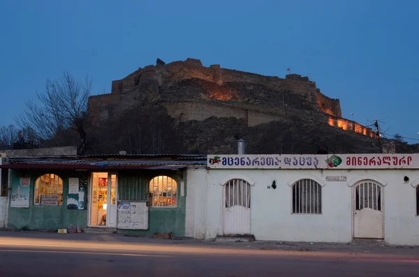 GORI, GEORGIA - MARCH 6, 2015: Night view of Gori fortress located on hill from street market,Georgia,Caucasus.It was important military stronghold in Middle Ages — Stock Photo, Image