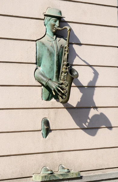 : 萨克斯管吹奏者穿过墙老第比利斯，格鲁吉亚鲁斯塔韦利大街上的青铜雕像 — 图库照片