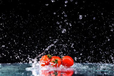 Stüdyo ile vurdu Don cherry domates kopya alanı siyah zemin üzerine su sıçrama içinde hareket