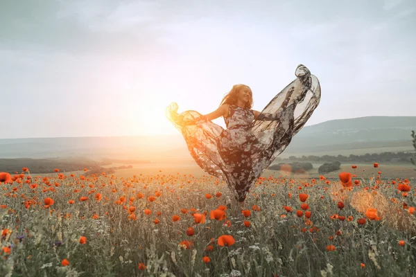 Bella ragazza in un campo di papaveri al tramonto. concetto di libertà — Foto Stock