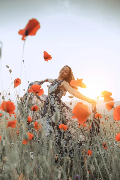 Bella ragazza in un campo di papaveri al tramonto. concetto di libertà — Foto Stock