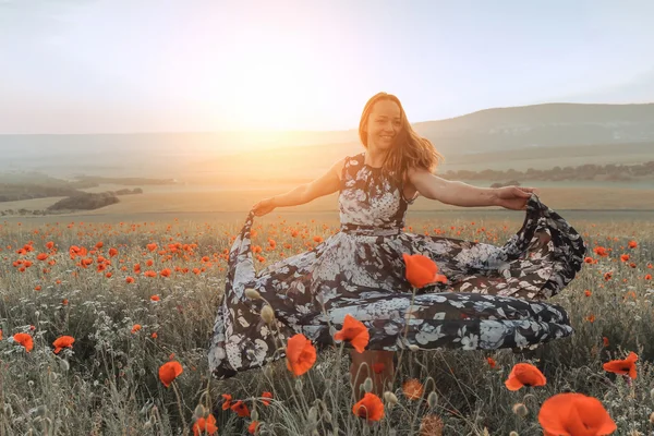 Bella ragazza in un campo di papaveri al tramonto. concetto di libertà — Foto Stock