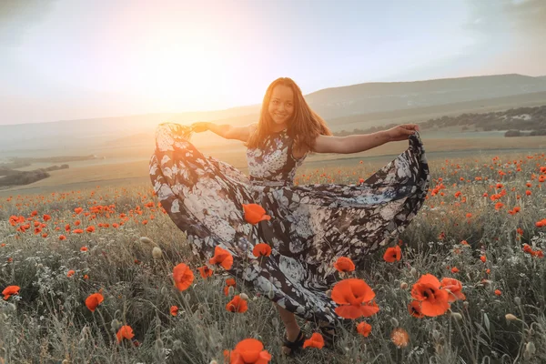 Bella ragazza in un campo di papaveri al tramonto. concetto di libertà — Foto Stock