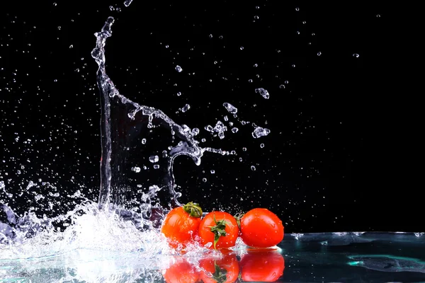 Studio shot with freeze motion of cherry tomatoes in water splash on black background with copy space — Stock Photo, Image