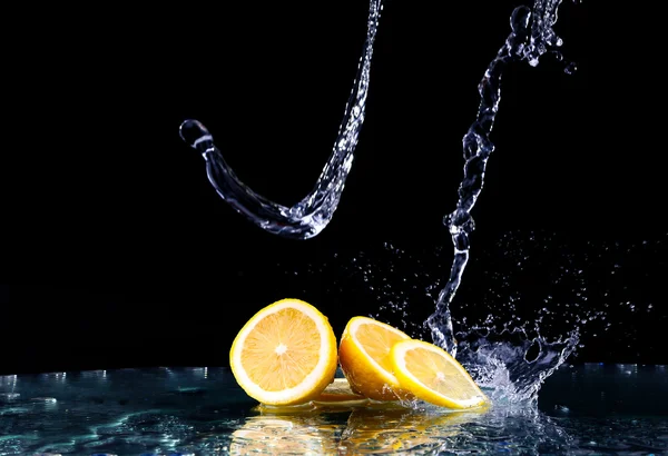 Limão fatiado na água sobre fundo preto — Fotografia de Stock