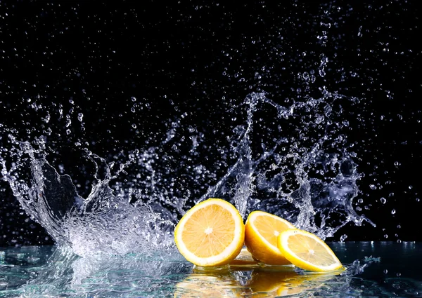 Szeletelt citrom a vízben, a fekete háttér — Stock Fotó