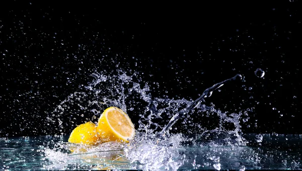 Skåret citron i vandet på sort baggrund - Stock-foto