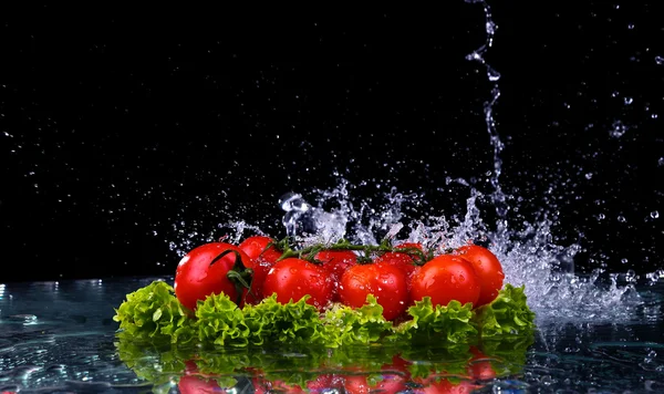 Färska tomater körsbär och grön färsk sallad med vatten droppe stänk på mörk bakgrund makro droppar vatten falla på röda körsbärstomater och göra splash — Stockfoto