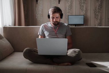 Evde kulaklıklı ve defterli bir adam var. Genç hipster internetten kulaklık takıyor. Dizüstü bilgisayarda Webinar Podcast izliyor. Eğitim kursu ya da müzik dinliyor.