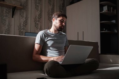 Uzaktan kumanda. Dizüstü bilgisayarda çalışan bir adam evdeki koltukta oturuyor. Metin için Boşluğu Kopyala. Serbest çalışan hipster, ortaklarıyla çalışır, çalışır ya da iletişim kurar.