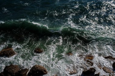 Okyanus dalgası arka planı deniz suyunu kırıyor kayalık kıyı dalgalı deniz turkuaz su gradyan köpüğü. Açık denizde büyük dalgalar. Yaz musonu. Bir deniz dalgasının beyaz tepesi.