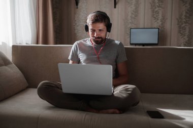 Evde kulaklıklı ve defterli bir adam var. Genç hipster internetten kulaklık takıyor. Dizüstü bilgisayarda Webinar Podcast izliyor. Eğitim kursu ya da müzik dinliyor.