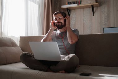 Evde kulaklıklı ve defterli bir adam var. Genç hipster internetten kulaklık takıyor. Dizüstü bilgisayarda Webinar Podcast izliyor. Eğitim kursu ya da müzik dinliyor.