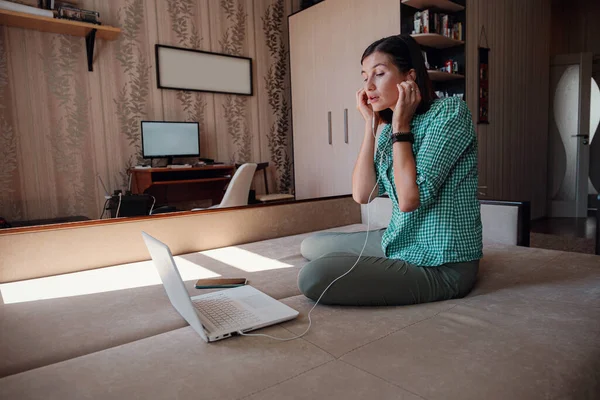 Young attractive woman on sofa working on new project with laptop in home. Attractive businesswoman studying online, using laptop software, web surfing information or shopping in internet store.