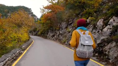 Güzel gülümseyen Asyalı kadın sonbahar yollarında yürüyor, etrafa bakıyor, doğanın güzelliğinden zevk alıyor. Yürüyüş, hobi, rahatlama, dinlenme zamanı. Ara veriyoruz..