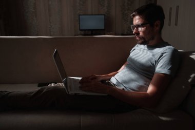 Uzaktan kumanda. Dizüstü bilgisayarda çalışan bir adam evdeki koltukta oturuyor. Metin için Boşluğu Kopyala. Serbest çalışan hipster, ortaklarıyla çalışır, çalışır ya da iletişim kurar.